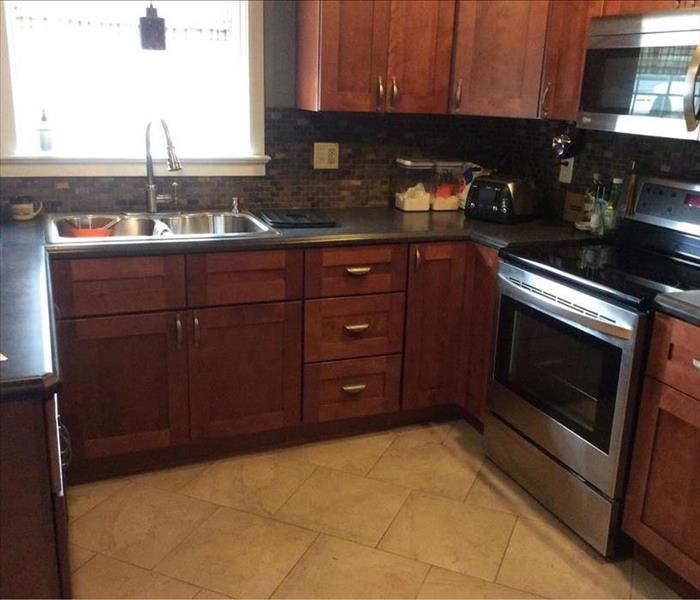 Kitchen with dark brown cupboards, black counter top and a stainless steel stove