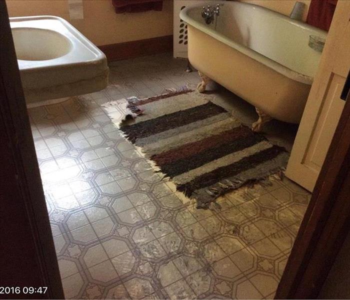 Black Soot on cream colored floor and frayed red striped rug in bathroom
