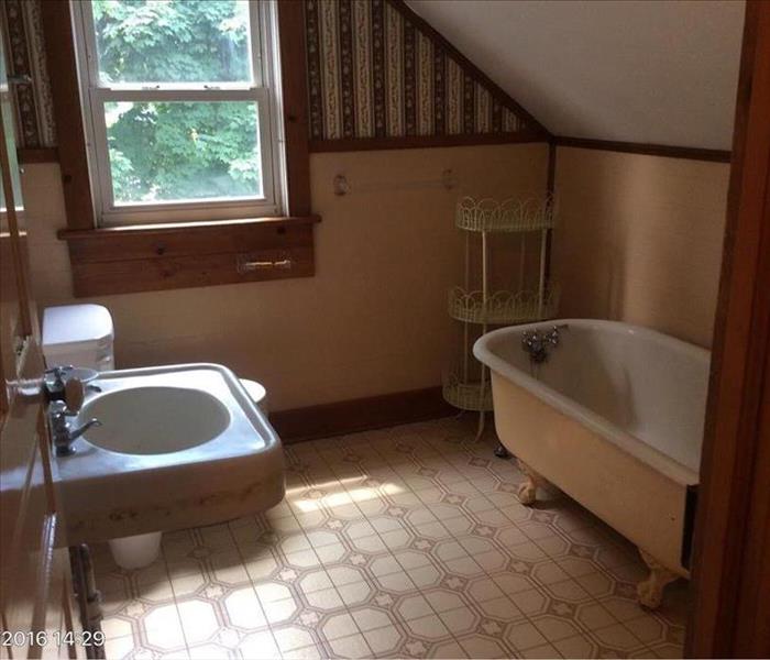 Cream colored bathroom with sink, toilet, rub and shelving unit