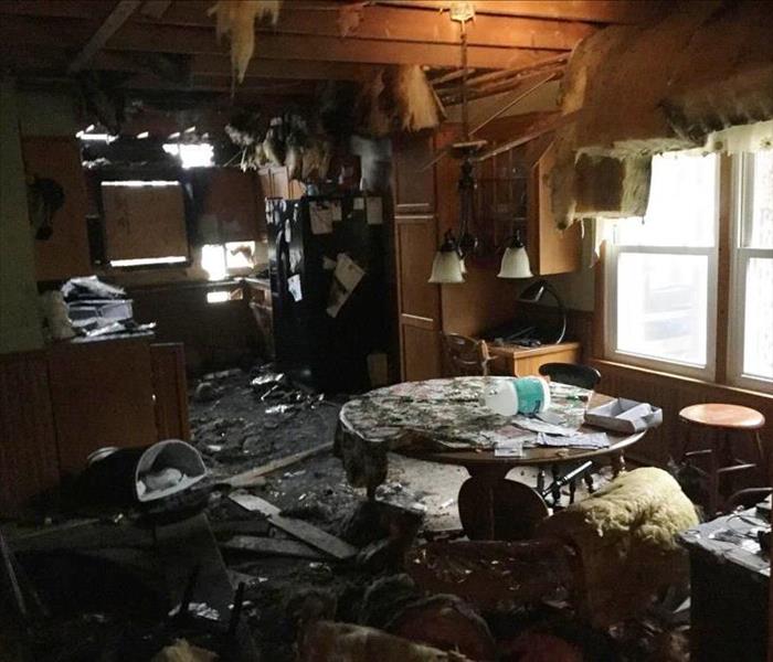 Dining room with ceiling insulation hanging down, and soot and debris all over