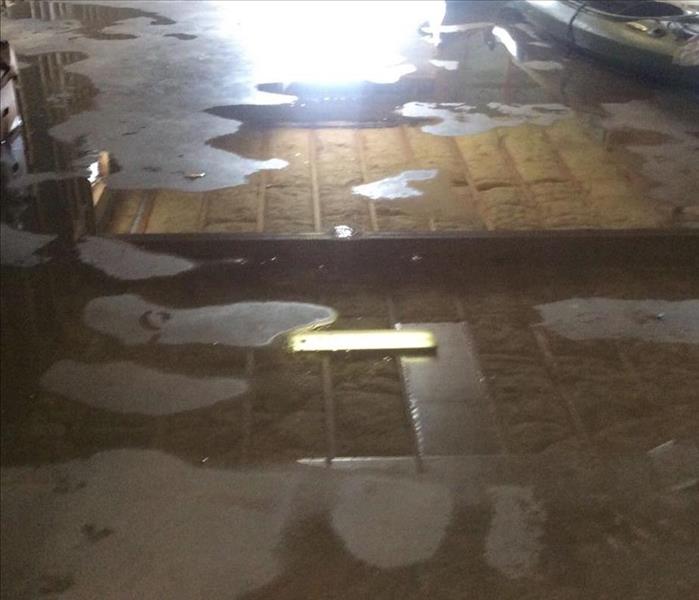 Puddles of water on concrete floor with kayaks in the background