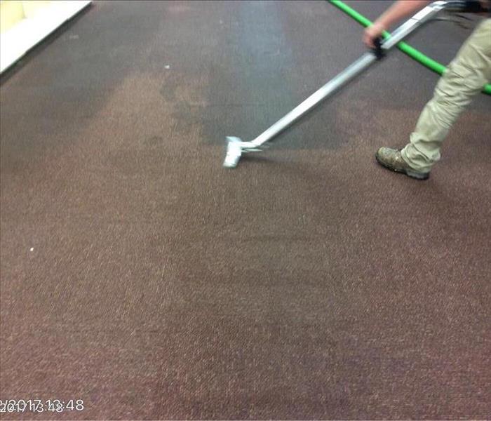 Person extracting water from brown carpet